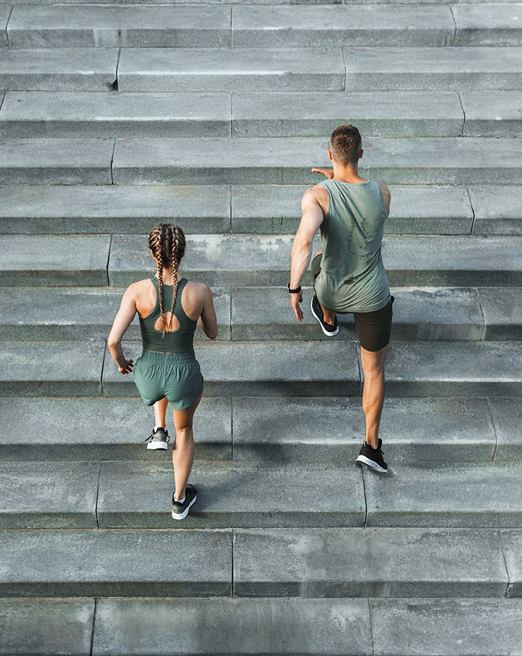 a male and female sprinting up an outdoor staircase