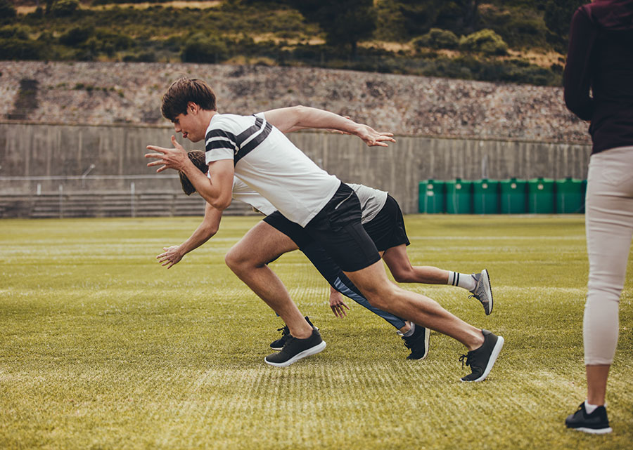 two young men leaning into a sprinters pose at the start of a race